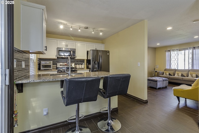 4422 SW Appletree Pl, Beaverton, OR 97078 - kitchen with appliances with stainless steel finishes, stone countertops, a peninsula, tasteful backsplash, and white cabinetry