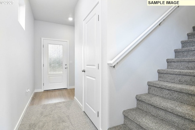 stairs with baseboards, carpet floors, and wood finished floors