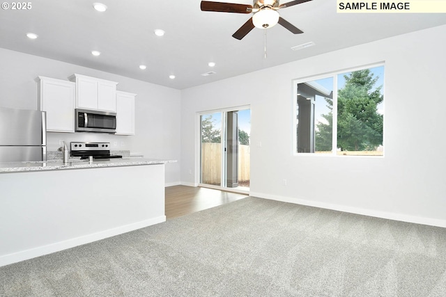 kitchen featuring light carpet, light stone counters, white cabinetry, appliances with stainless steel finishes, and ceiling fan