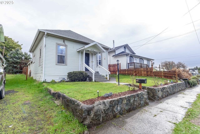 view of front of home featuring roof with shingles, fence, and a front yard