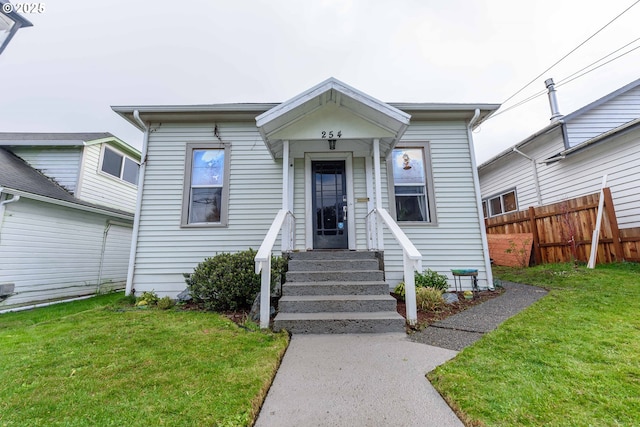 view of front facade featuring entry steps, fence, and a front lawn