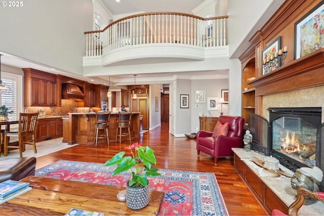 living room featuring a glass covered fireplace, baseboards, dark wood-style flooring, and a high ceiling