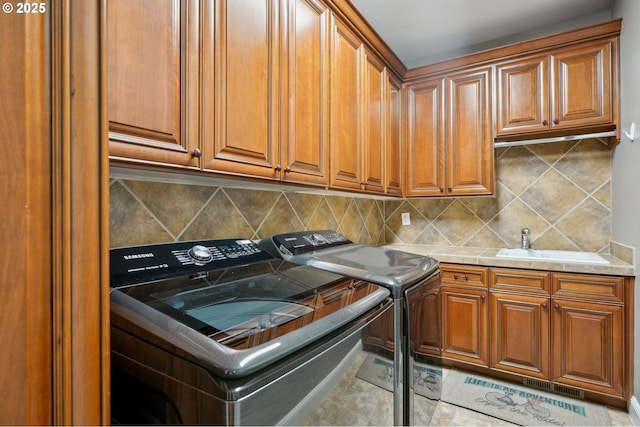 laundry area with a sink, washer and dryer, cabinet space, and visible vents