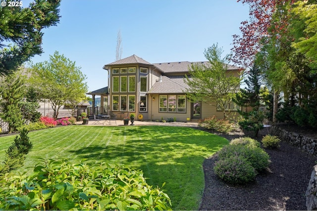 back of property with a patio, a lawn, and fence