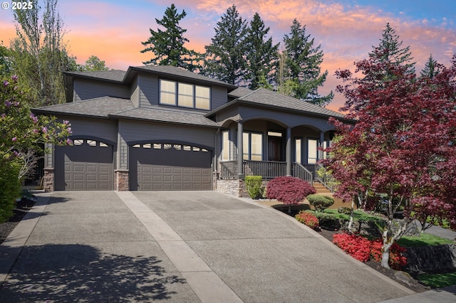 prairie-style house featuring a garage, a shingled roof, covered porch, stone siding, and concrete driveway