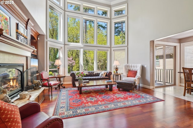 living area featuring a high ceiling, a premium fireplace, wood finished floors, and baseboards