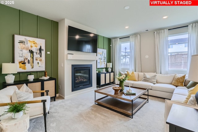 carpeted living area featuring recessed lighting, visible vents, and a glass covered fireplace