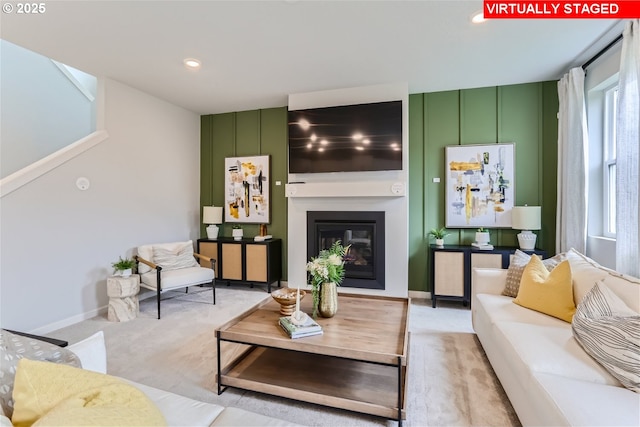 living area with a glass covered fireplace, light carpet, baseboards, and recessed lighting