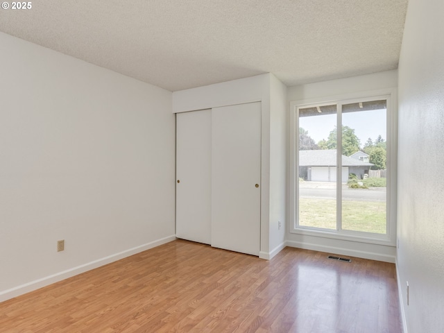 20270 SW Brightwood Ct, Beaverton, OR 97003 - unfurnished bedroom featuring light wood-style floors, a textured ceiling, multiple windows, baseboards, and a closet