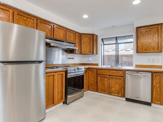20270 SW Brightwood Ct, Beaverton, OR 97003 - kitchen featuring appliances with stainless steel finishes, under cabinet range hood, a sink, brown cabinetry, and recessed lighting