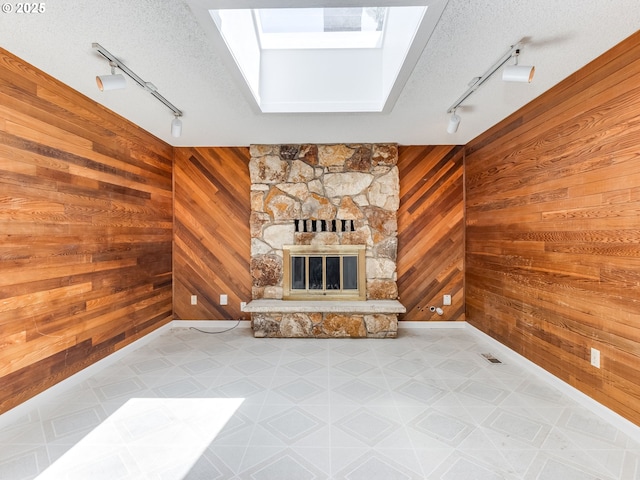 20270 SW Brightwood Ct, Beaverton, OR 97003 - unfurnished living room with track lighting, wood walls, a skylight, a stone fireplace, and tile patterned floors