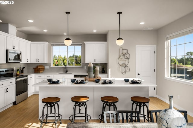 kitchen featuring backsplash, appliances with stainless steel finishes, a breakfast bar, and a sink