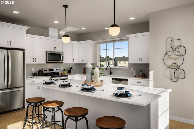 kitchen with decorative backsplash, light wood-style flooring, a kitchen bar, and stainless steel appliances