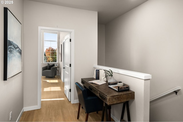 hall with baseboards, light wood-type flooring, and an upstairs landing