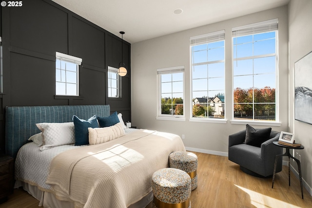 bedroom featuring baseboards, multiple windows, and wood finished floors