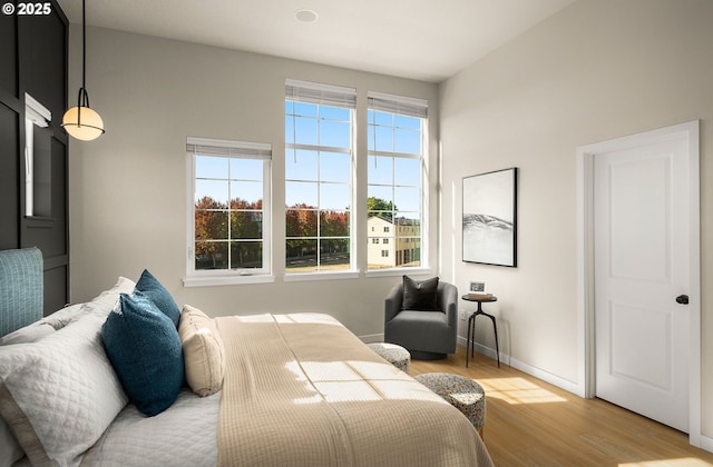 bedroom with light wood-type flooring, baseboards, and multiple windows