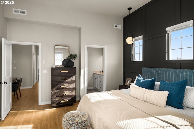 bedroom with light wood-style floors, baseboards, multiple windows, and visible vents