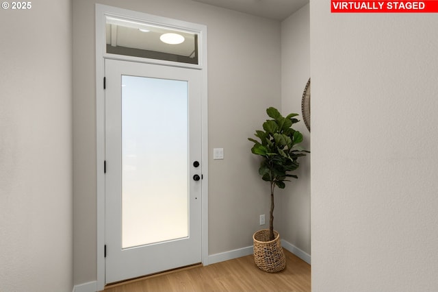 doorway to outside with baseboards and light wood finished floors