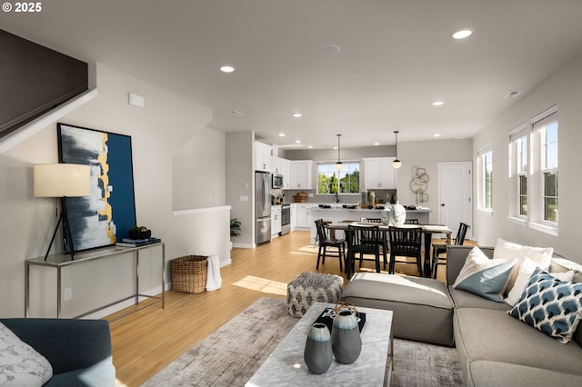 living room with recessed lighting, baseboards, and light wood-style floors