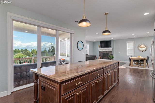 kitchen with dark wood-style flooring, light stone counters, a fireplace, baseboards, and pendant lighting