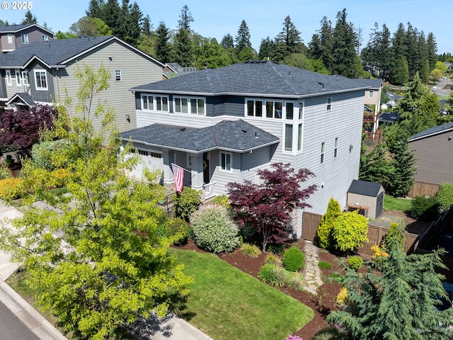 exterior space with a storage shed, fence, an outdoor structure, and roof with shingles