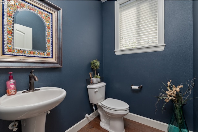 bathroom with a sink, baseboards, toilet, and wood finished floors
