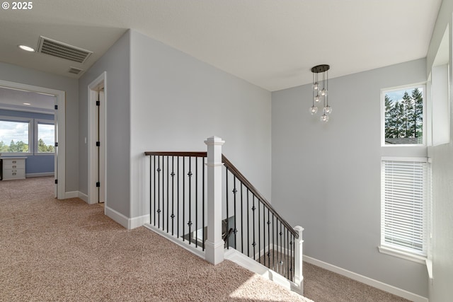 interior space with visible vents, carpet, baseboards, and an upstairs landing