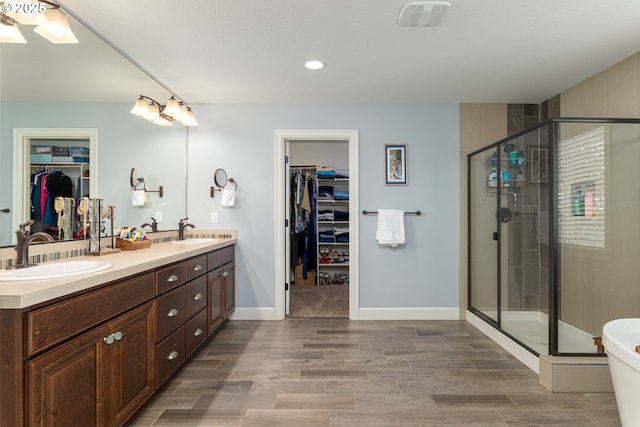 full bath featuring double vanity, a sink, a stall shower, and wood finished floors