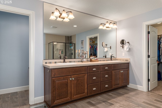 full bathroom with double vanity, a sink, a stall shower, and wood finished floors