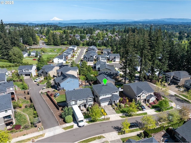 drone / aerial view featuring a wooded view, a mountain view, and a residential view