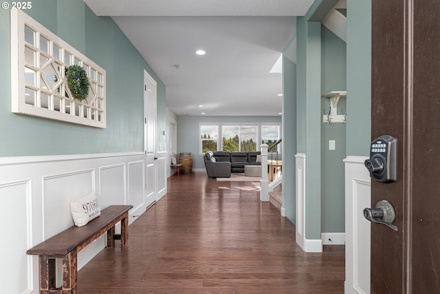 corridor with wood finished floors, stairway, a wainscoted wall, a decorative wall, and recessed lighting