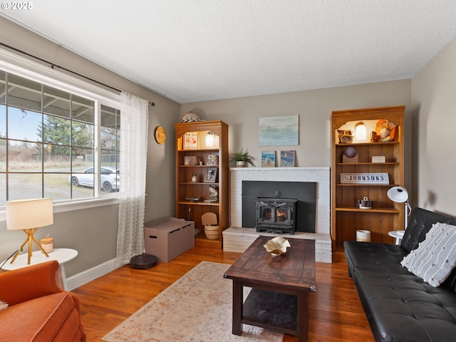 living room featuring wood-type flooring, a textured ceiling, and a wood stove