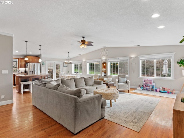 living room featuring a textured ceiling, vaulted ceiling, french doors, a chandelier, and light wood-type flooring