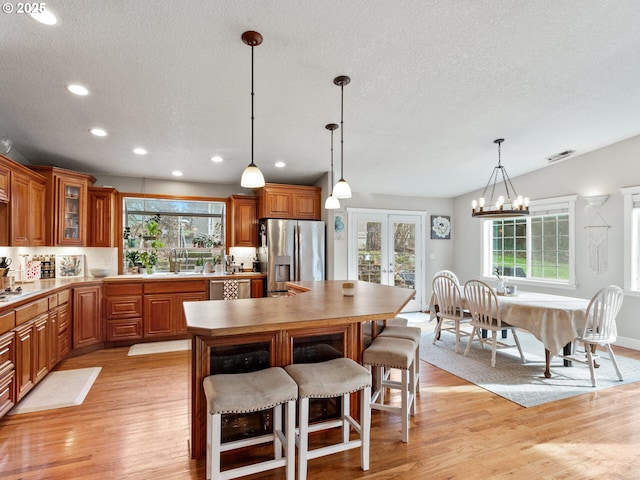 kitchen with sink, appliances with stainless steel finishes, light hardwood / wood-style floors, decorative light fixtures, and french doors