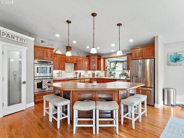 kitchen featuring appliances with stainless steel finishes, a kitchen bar, a kitchen island, and light hardwood / wood-style flooring