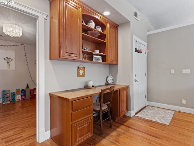 home office featuring built in desk, a textured ceiling, and light wood-type flooring