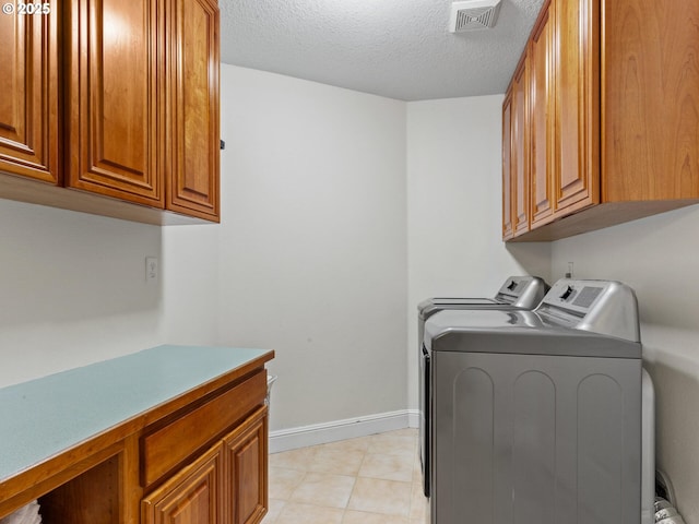 clothes washing area featuring a textured ceiling, cabinets, and washing machine and clothes dryer