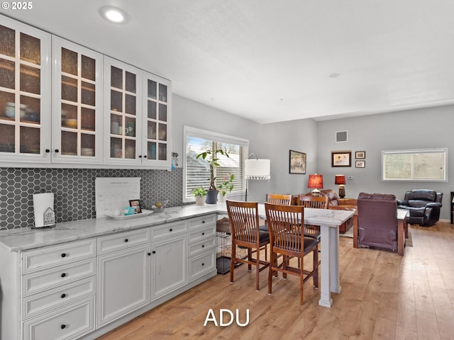 kitchen with decorative backsplash, light hardwood / wood-style flooring, and white cabinets