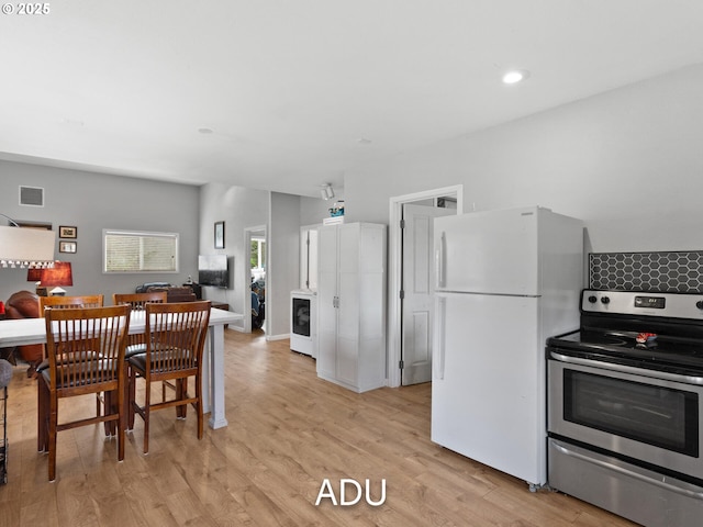 kitchen featuring stainless steel electric range oven, washer / dryer, white fridge, and light hardwood / wood-style flooring