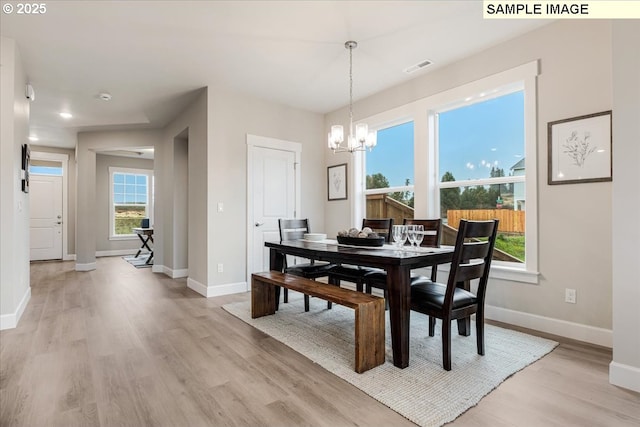 dining space with an inviting chandelier and light hardwood / wood-style flooring