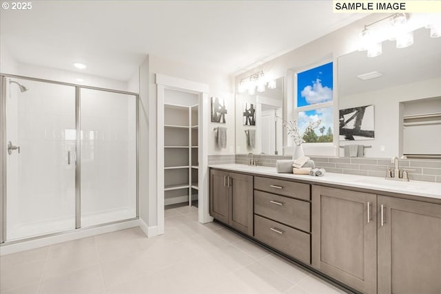 bathroom featuring vanity, backsplash, a shower with shower door, and tile patterned floors