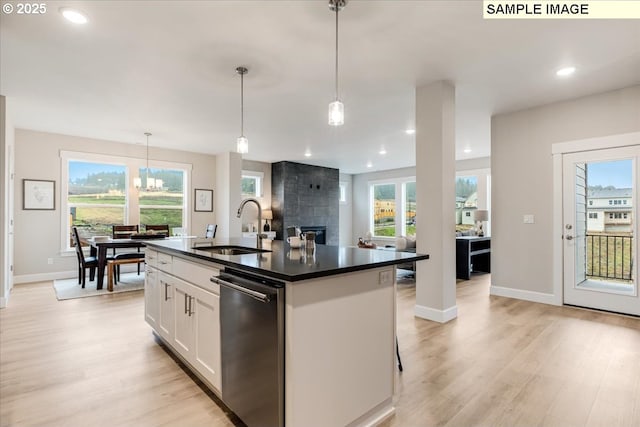 kitchen featuring white cabinetry, hanging light fixtures, sink, and an island with sink