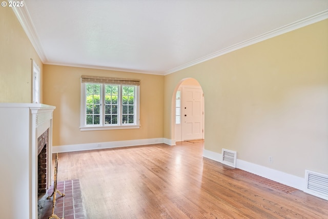 1702 24th Ave, Longview, WA 98632 - unfurnished living room featuring crown molding, wood finished floors, arched walkways, and a brick fireplace