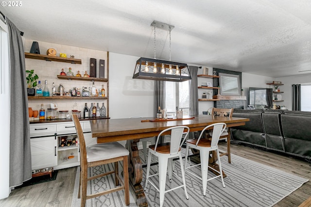 dining area featuring plenty of natural light, a textured ceiling, wood finished floors, and a dry bar