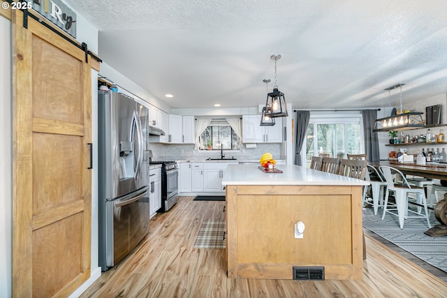 kitchen with visible vents, a sink, a barn door, appliances with stainless steel finishes, and light countertops