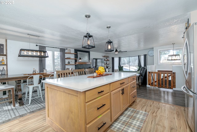 kitchen with a wealth of natural light, light wood finished floors, light brown cabinets, and freestanding refrigerator