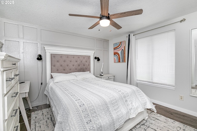 bedroom featuring ceiling fan, wood finished floors, baseboards, and a textured ceiling