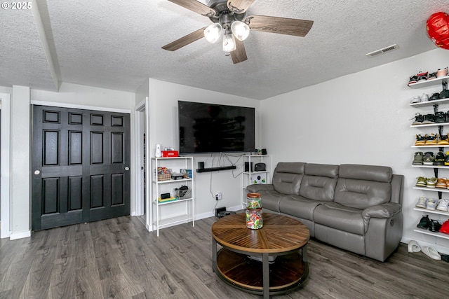 living area featuring a ceiling fan, wood finished floors, visible vents, and a textured ceiling