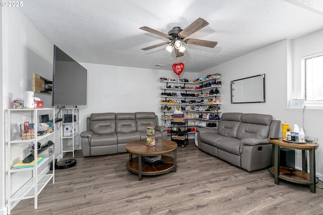 living room featuring ceiling fan, a textured ceiling, and wood finished floors