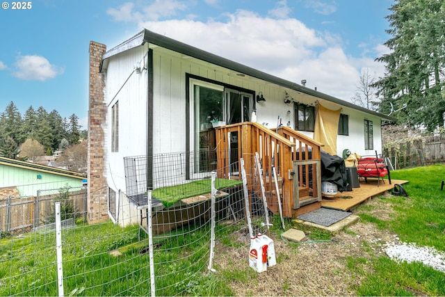 rear view of house featuring a lawn and fence